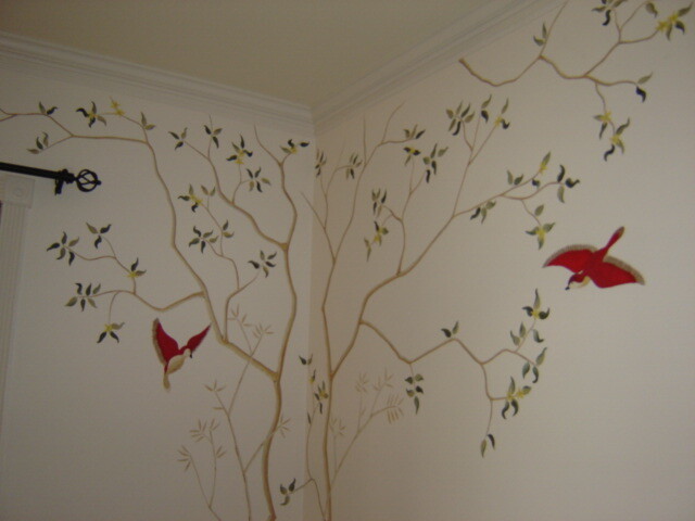 Hand-painted branches and red birds extending across a bedroom wall